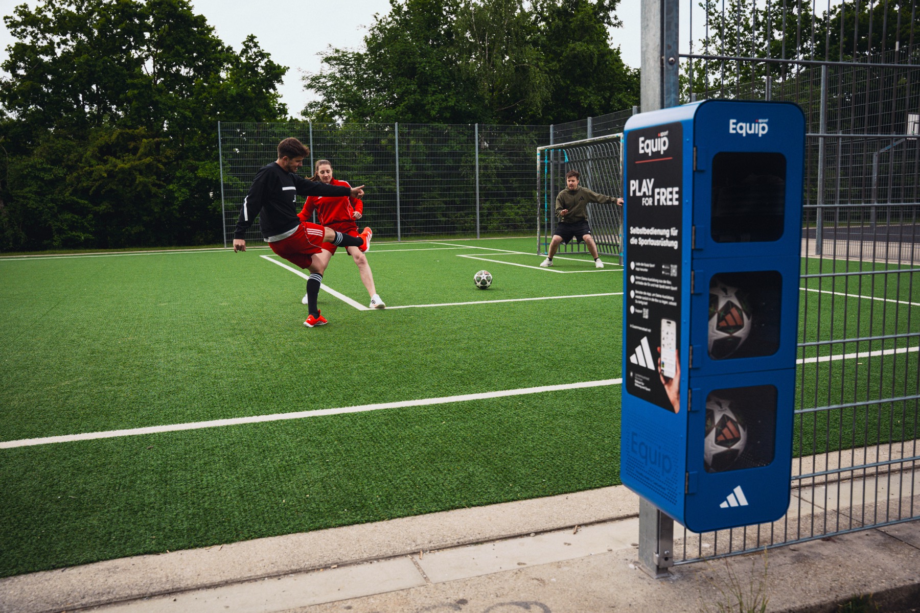 A pickup game on an artificial pitch beside a station.