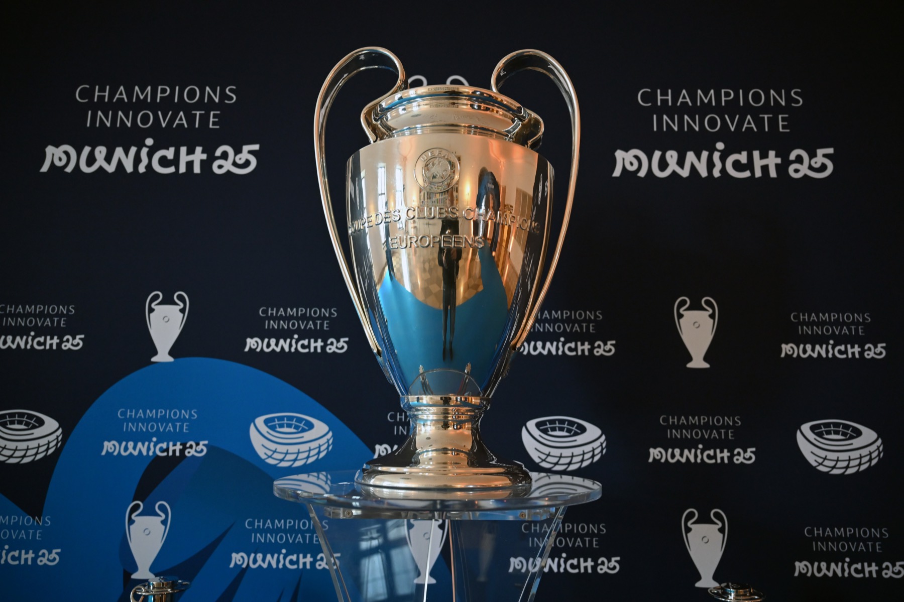 The UEFA Champions League trophy in front of the Champions Innovate Munich 25 backdrop.